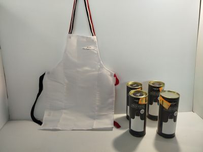 un tablier blanc et deux canettes de bière posées sur une table