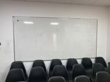 rows of black chairs in front of a white board in a room