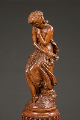 a wooden statue of a woman sitting on top of a table