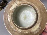 a person holding a plate with a small bowl on it