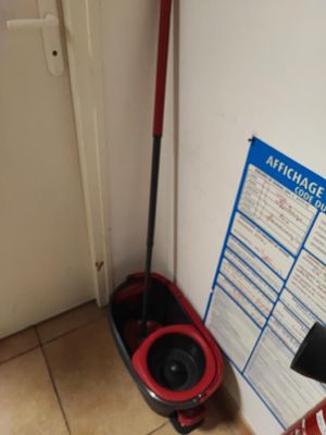 a mop and a bucket next to a sign on the wall