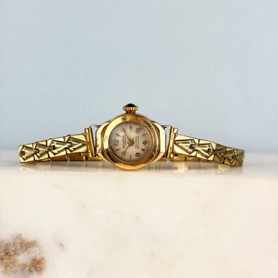 une photo d'une montre-bracelet en or posée sur un comptoir en marbre