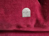 a close up of a red shirt with a silver coin on it