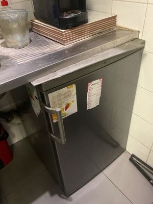 a small silver refrigerator in a kitchen with a coffee maker