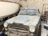 a old car parked in a garage next to a boat
