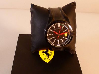 une montre posée sur un oreiller orné du logo Ferrari
