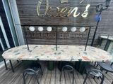 une table et des chaises sur une terrasse, avec une pancarte au-dessus