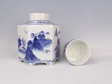 a blue and white vase and a white cup on a table