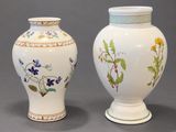 two white vases with floral designs on them sitting side by side
