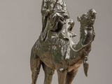 bronze statue of a man riding a camel with a spear in his hand