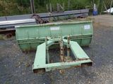 a green dumpster sitting in the gravel next to a pile of metal