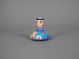 un vase bleu orné de fleurs, posé sur une surface grise