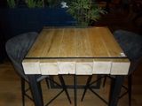 a wooden table with four stools and a plant in the background