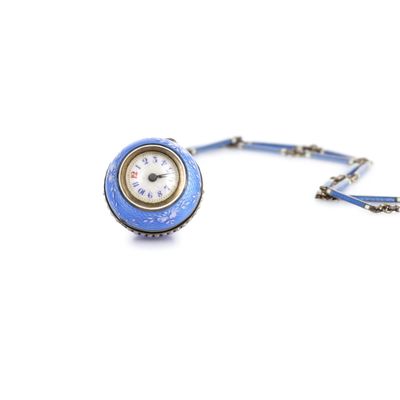 une petite horloge bleue suspendue à une chaîne sur fond blanc