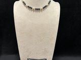 a black and white beaded necklace on a mannequin with a pillow