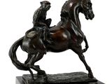 bronze statue of a man riding a horse on a marble base