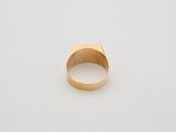 a gold signet ring on a white surface