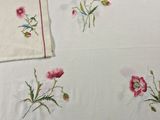 embroidered tablecloths with pink flowers and green stems on a white table