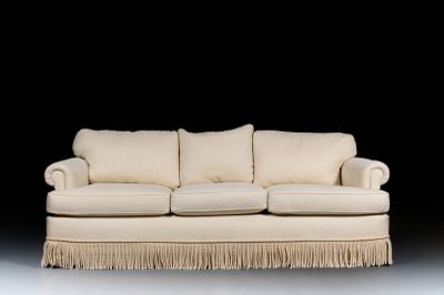 a white couch with fringes on it in a dark room