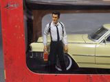 boxed picture of a toy car with a man in a tie standing in front of it