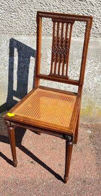 a wooden chair sitting next to a wall on the sidewalk