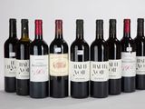 six bouteilles de vin rouge alignées sur une surface blanche