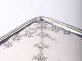 a silver tray with flowers on it sitting on a table