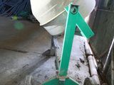a cement mixer sitting in a garage with a green handle