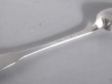 an antique silver spoon with a spoon handle on a white surface