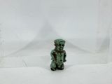 an image of a small green figurine sitting on top of a white surface