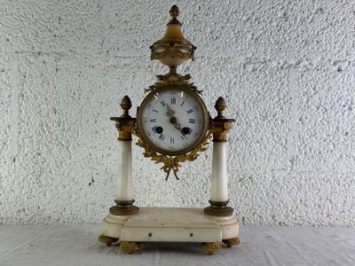 une petite horloge posée sur une table, avec un mur blanc en arrière-plan
