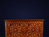 un coffre ancien en bois orné d'un motif floral sur le devant