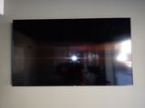 a television mounted on the wall with a person taking a picture of it