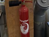 un extincteur fixé au mur à côté d'une borne d'incendie