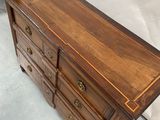 a wooden dresser with drawers and a chair in the background