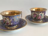 two cups and saucers sitting on top of a white table