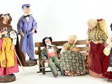 five figurines of people sitting on a bench