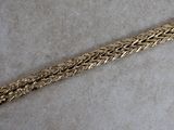 gros plan d'un bracelet en or sur une surface blanche