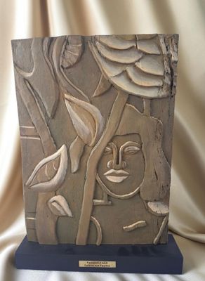 sculpture représentant un visage sur un bloc de pierre, ornée de feuilles et de fleurs