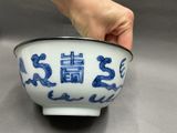 a hand holding a blue and white bowl on a table