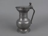 an antique silver pitcher with a handle on a gray background
