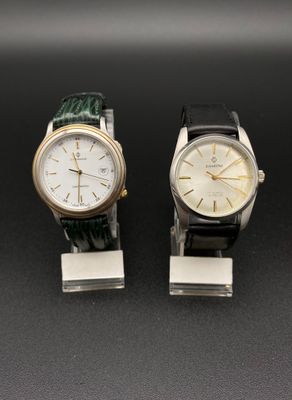 Deux montres sont posées côte à côte sur une surface noire.