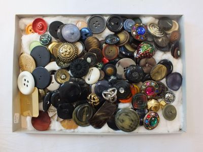 une boîte remplie de boutons assortis posée sur une surface blanche