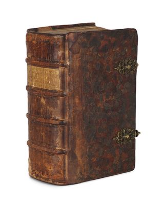 un vieux livre à la couverture brune posé sur une surface blanche