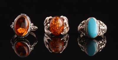 trois bagues ornées de pierres de différentes couleurs sur un fond noir