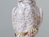 une figurine représentant un hibou blanc posée sur une table en bois