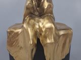 bronze sculpture of a woman sitting on a rock with a hood on her head