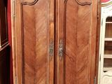 une armoire en bois à deux portes avec une étagère, placée devant un mur rouge
