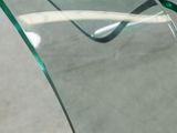 a glass table with a curved glass top on the floor
