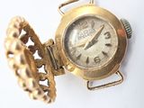 a gold watch with a chain around it on a white surface